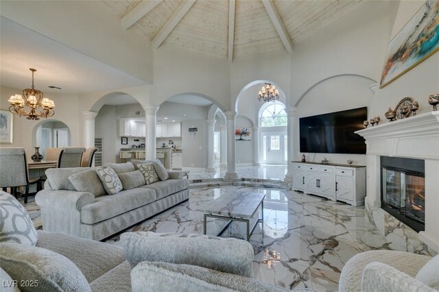 2101 Diamond Bar Dr, Las Vegas, NV 89117 - living room featuring high vaulted ceiling, ornate columns, light marble finish floors, a chandelier, and arched walkways