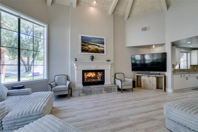 2101 Diamond Bar Dr, Las Vegas, NV 89117 - living area featuring light wood-style floors, a glass covered fireplace, wooden ceiling with exposed beams, and high vaulted ceiling