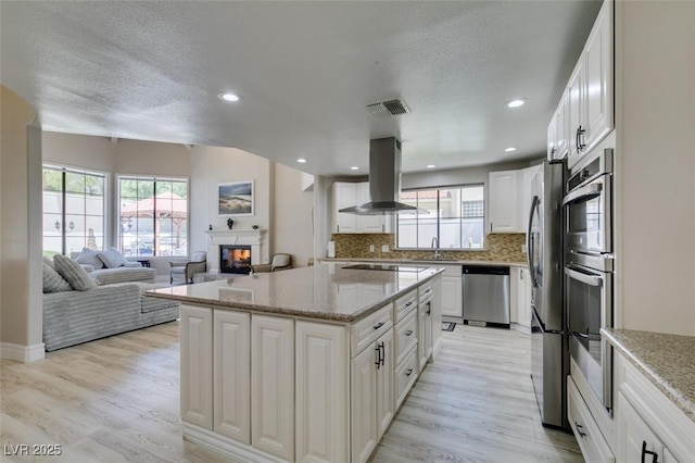 2101 Diamond Bar Dr, Las Vegas, NV 89117 - kitchen with stainless steel appliances, island range hood, a sink, a glass covered fireplace, and a center island