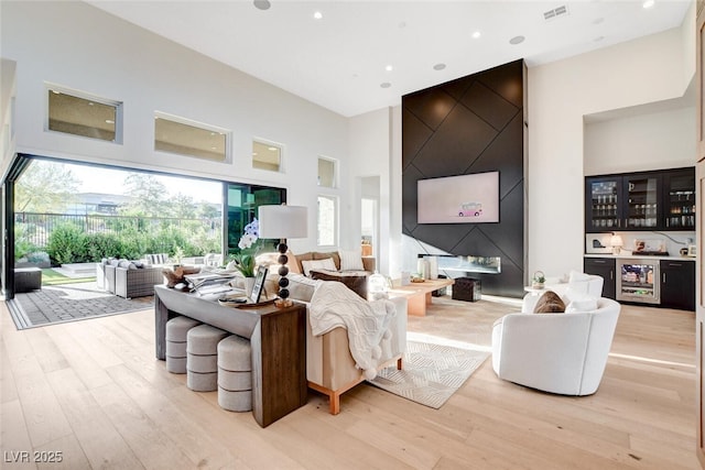 5155 Rock Daisy Dr, Las Vegas, NV 89135 - living room with wine cooler, a towering ceiling, light wood finished floors, a dry bar, and recessed lighting