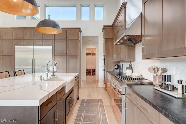 5155 Rock Daisy Dr, Las Vegas, NV 89135 - kitchen with high quality appliances, a sink, wall chimney range hood, hanging light fixtures, and tasteful backsplash