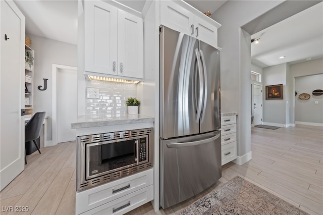 2816 High Range Dr, Las Vegas, NV 89134 - kitchen featuring appliances with stainless steel finishes, white cabinetry, light stone counters, light wood-style flooring, and baseboards