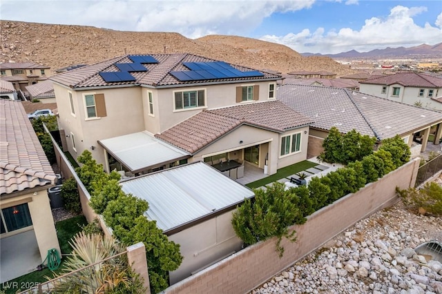 3929 Reyes Ave, Las Vegas, NV 89141 - rear view of property with stucco siding, roof mounted solar panels, a mountain view, a fenced backyard, and a tile roof