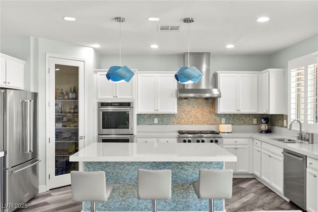 424 Vigo Port St, Las Vegas, NV 89138 - kitchen featuring appliances with stainless steel finishes, wall chimney exhaust hood, a sink, light wood-style flooring, and light countertops