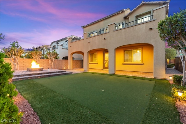 424 Vigo Port St, Las Vegas, NV 89138 - rear view of house featuring a putting area, a balcony, a patio area, stucco siding, and a fire pit