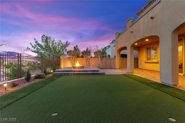 424 Vigo Port St, Las Vegas, NV 89138 - fenced backyard featuring an outdoor fire pit, a patio area, and a putting area