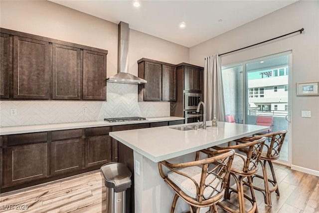 2507 Silent View Ave, Henderson, NV 89044 - kitchen with wall chimney range hood, a sink, light countertops, light wood-style flooring, and tasteful backsplash