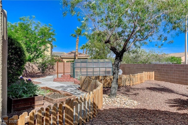 5949 Casa Coronado Ave, Las Vegas, NV 89131 - fenced backyard featuring a greenhouse, a vegetable garden, and an outbuilding