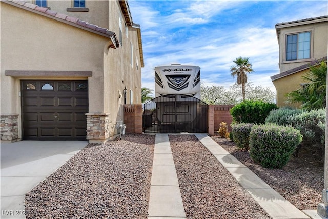 5949 Casa Coronado Ave, Las Vegas, NV 89131 - view of side of property with a gate, stucco siding, stone siding, concrete driveway, and a garage