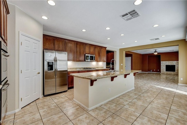 5949 Casa Coronado Ave, Las Vegas, NV 89131 - kitchen featuring stainless steel appliances, a breakfast bar, light tile patterned flooring, light stone counters, and recessed lighting