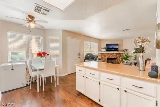 904 Boulder Springs Dr Unit 102, Las Vegas, NV 89128 - kitchen with white cabinets, a fireplace, wood finished floors, and light countertops