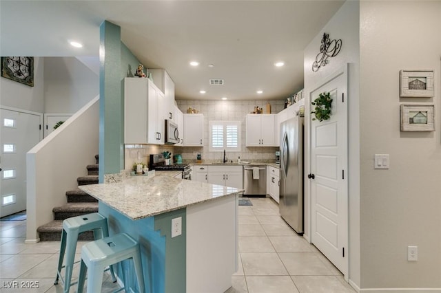 4519 Sapphire Moon Ave, North Las Vegas, NV 89084 - kitchen with stainless steel appliances, a peninsula, a sink, light stone countertops, and a breakfast bar area