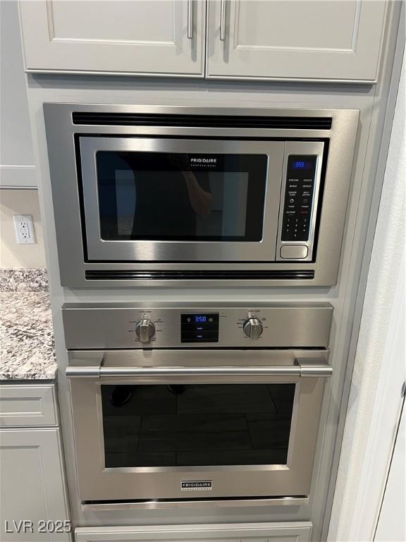 7265 Southern Magnolia St, Las Vegas, NV 89149 - kitchen view of appliances with stainless steel finishes, white cabinetry, and light stone countertops