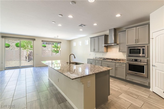 7265 Southern Magnolia St, Las Vegas, NV 89149 - kitchen featuring appliances with stainless steel finishes, wall chimney range hood, a sink, gray cabinetry, and light stone counters