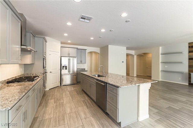 7265 Southern Magnolia St, Las Vegas, NV 89149 - kitchen featuring appliances with stainless steel finishes, arched walkways, gray cabinetry, a sink, and an island with sink