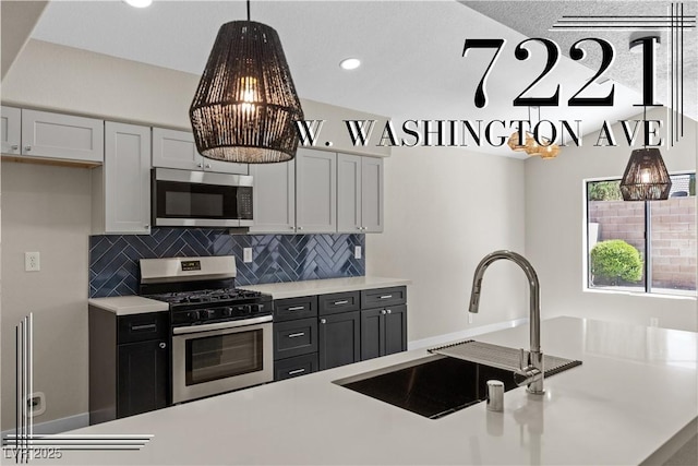 7221 W Washington Ave, Las Vegas, NV 89128 - kitchen with appliances with stainless steel finishes, a sink, light countertops, tasteful backsplash, and pendant lighting