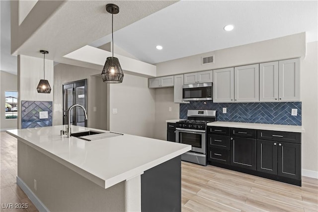 7221 W Washington Ave, Las Vegas, NV 89128 - kitchen with stainless steel appliances, tasteful backsplash, a sink, light countertops, and light wood finished floors