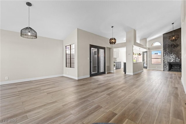 7221 W Washington Ave, Las Vegas, NV 89128 - unfurnished living room featuring high vaulted ceiling, light wood-style floors, baseboards, a tiled fireplace, and a sink