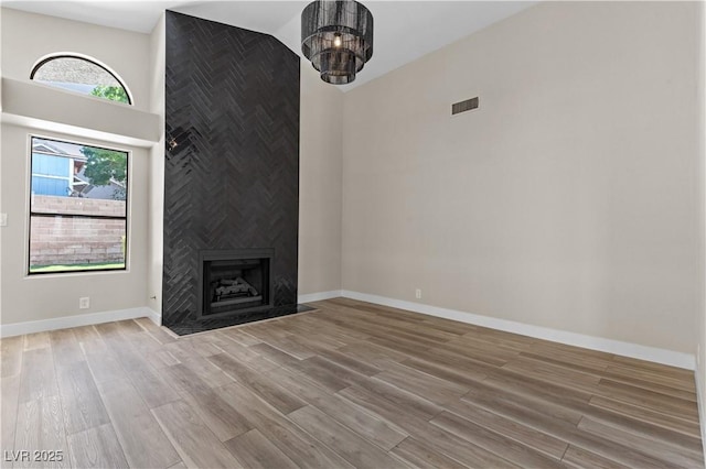7221 W Washington Ave, Las Vegas, NV 89128 - unfurnished living room featuring wood finished floors, baseboards, a large fireplace, and a high ceiling