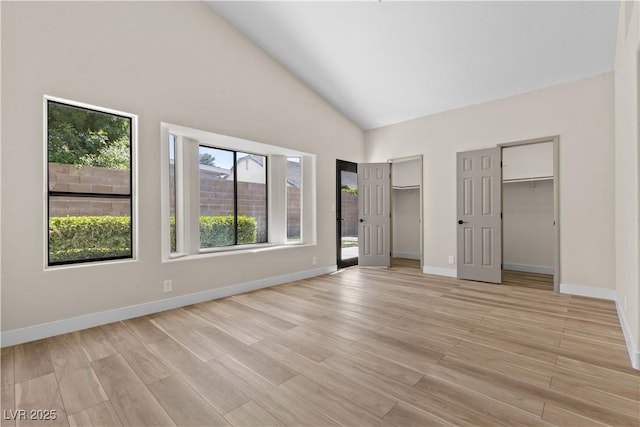 7221 W Washington Ave, Las Vegas, NV 89128 - unfurnished bedroom with light wood-style flooring, high vaulted ceiling, two closets, and baseboards