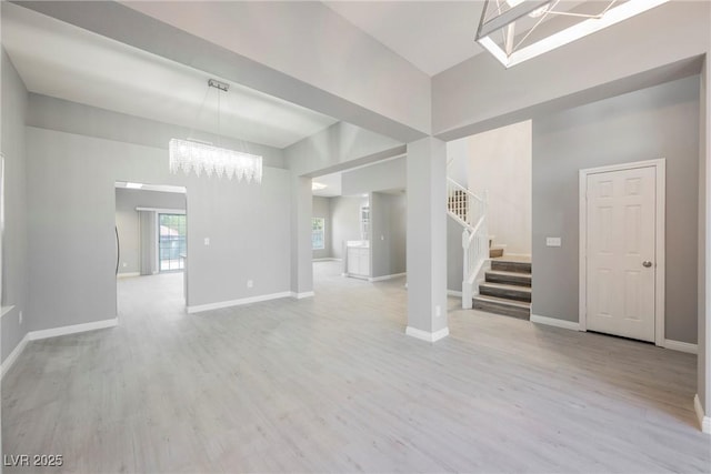 5133 Burr Oak Dr, Las Vegas, NV 89130 - unfurnished living room featuring a chandelier, stairway, a high ceiling, light wood finished floors, and baseboards