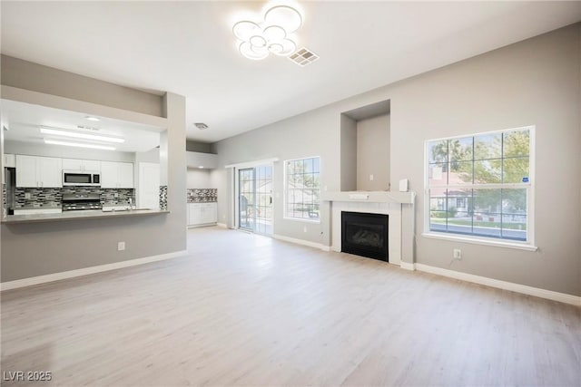 5133 Burr Oak Dr, Las Vegas, NV 89130 - unfurnished living room with light wood-style floors, a glass covered fireplace, and baseboards
