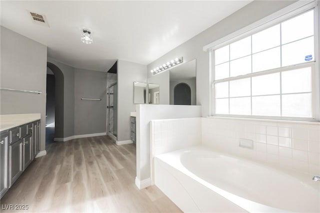 5133 Burr Oak Dr, Las Vegas, NV 89130 - bathroom with vanity, a garden tub, wood finished floors, baseboards, and a shower stall
