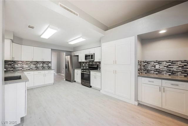 5133 Burr Oak Dr, Las Vegas, NV 89130 - kitchen featuring stainless steel appliances, tasteful backsplash, light wood-style floors, white cabinetry, and recessed lighting