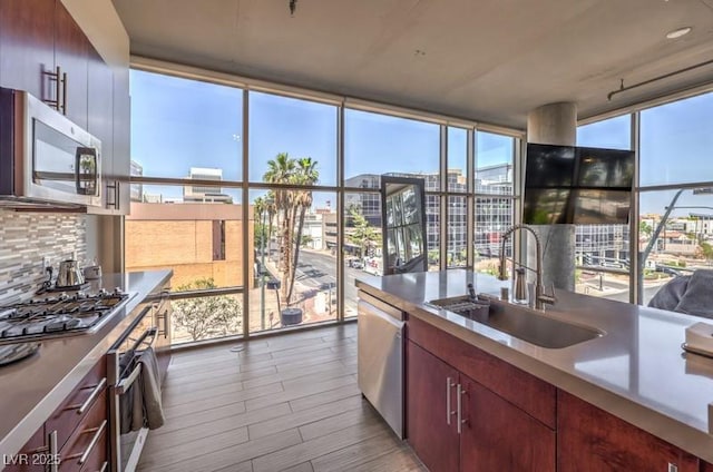 353 E Bonneville Ave Unit 379, Las Vegas, NV 89101 - kitchen with stainless steel appliances, a sink, a wall of windows, wood finished floors, and tasteful backsplash