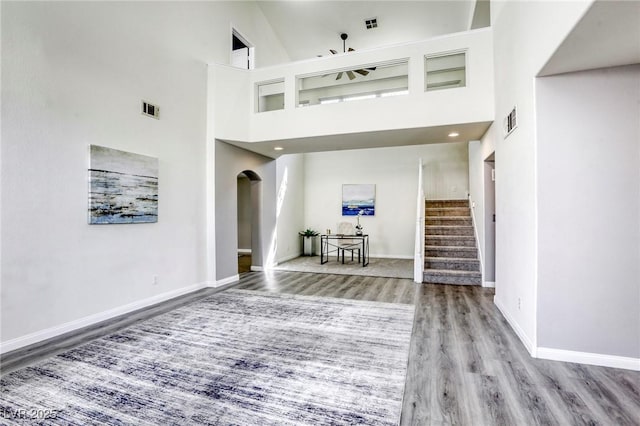 1833 Winners Cup Dr, Las Vegas, NV 89117 - living room featuring wood finished floors, baseboards, stairway, arched walkways, and a high ceiling