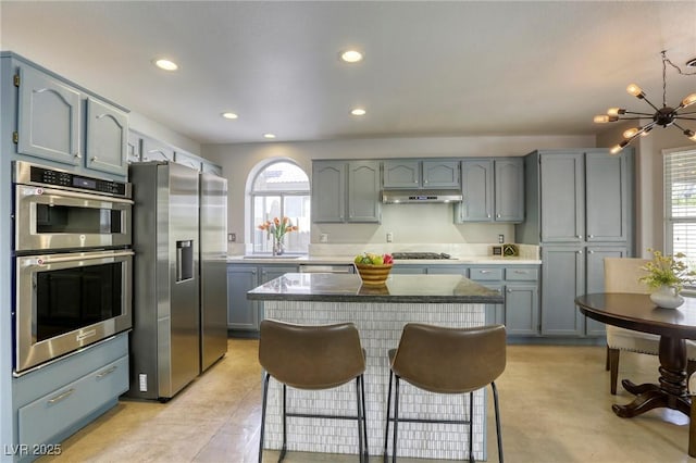 1833 Winners Cup Dr, Las Vegas, NV 89117 - kitchen with appliances with stainless steel finishes, recessed lighting, a chandelier, under cabinet range hood, and a breakfast bar