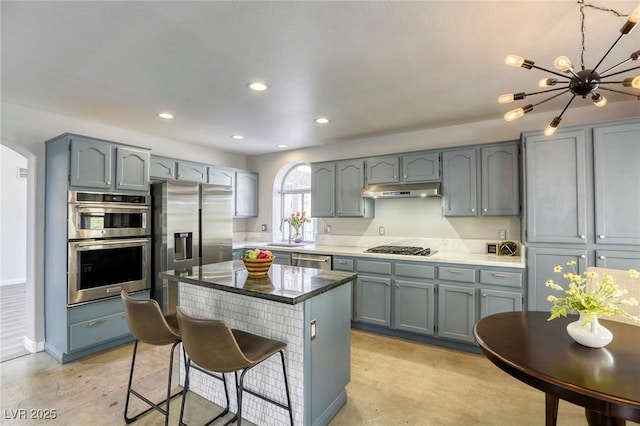 1833 Winners Cup Dr, Las Vegas, NV 89117 - kitchen featuring appliances with stainless steel finishes, a breakfast bar, under cabinet range hood, arched walkways, and a chandelier