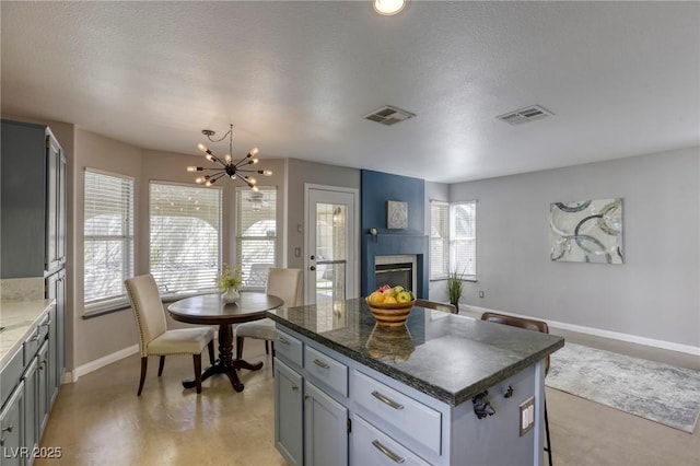 1833 Winners Cup Dr, Las Vegas, NV 89117 - kitchen featuring baseboards, a chandelier, a center island, a glass covered fireplace, and gray cabinetry