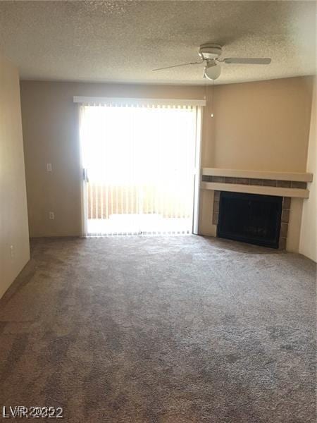 5220 Mission Carmel Ln Unit 207, Las Vegas, NV 89107 - unfurnished living room featuring a tile fireplace, carpet flooring, a ceiling fan, and a textured ceiling