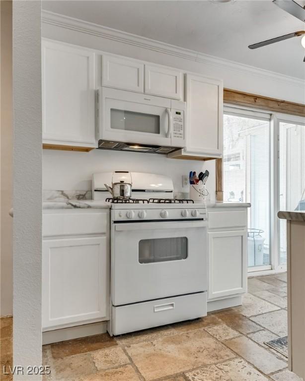 7950 Red Barn Dr, Las Vegas, NV 89123 - kitchen with white appliances, stone tile floors, ornamental molding, white cabinets, and a ceiling fan
