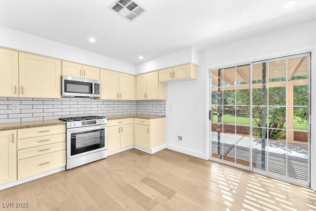 5216 Desert Star Dr, Las Vegas, NV 89130 - kitchen featuring stainless steel microwave, gas stove, cream cabinetry, light wood-style floors, and recessed lighting