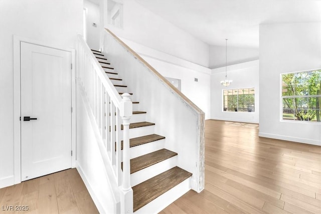 5216 Desert Star Dr, Las Vegas, NV 89130 - staircase with wood finished floors, a chandelier, high vaulted ceiling, and baseboards