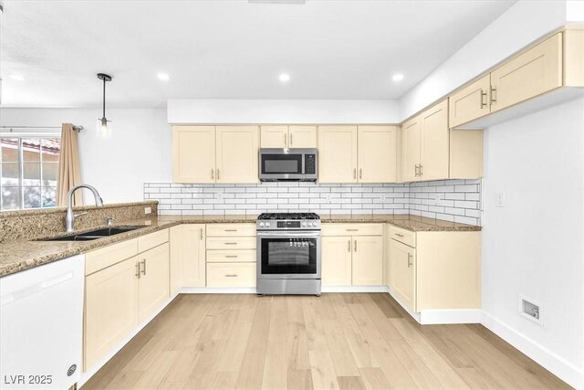 5216 Desert Star Dr, Las Vegas, NV 89130 - kitchen with appliances with stainless steel finishes, a sink, light stone counters, light wood-style flooring, and tasteful backsplash