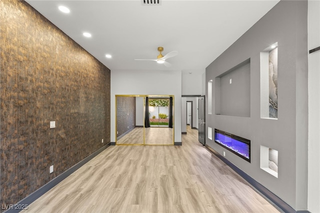 1616 Shadow Rock Dr, Las Vegas, NV 89117 - unfurnished living room with an accent wall, wood finished floors, a glass covered fireplace, ceiling fan, and recessed lighting