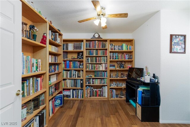905 White Thunder St, Henderson, NV 89002 - living area featuring wall of books, wood finished floors, a ceiling fan, and baseboards