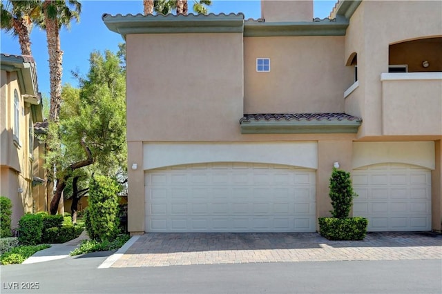 8717 Red Brook Dr Unit 201, Las Vegas, NV 89128 - view of front of house featuring a tile roof, an attached garage, stucco siding, and decorative driveway