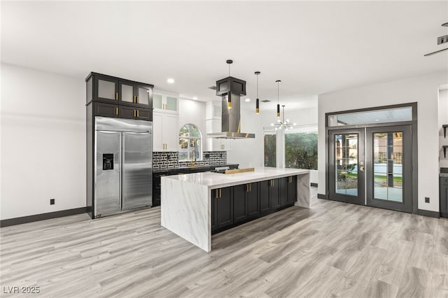 9029 Rivers Edge Dr, Las Vegas, NV 89117 - kitchen with stainless steel built in fridge, wall chimney range hood, light wood-type flooring, a center island, and a chandelier