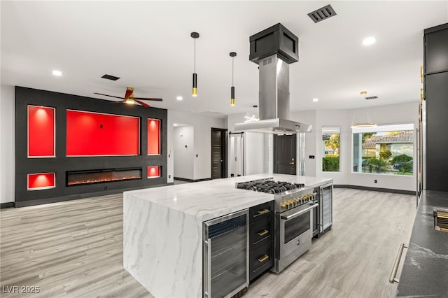 9029 Rivers Edge Dr, Las Vegas, NV 89117 - kitchen with wine cooler, stainless steel stove, island range hood, light wood-style floors, and recessed lighting