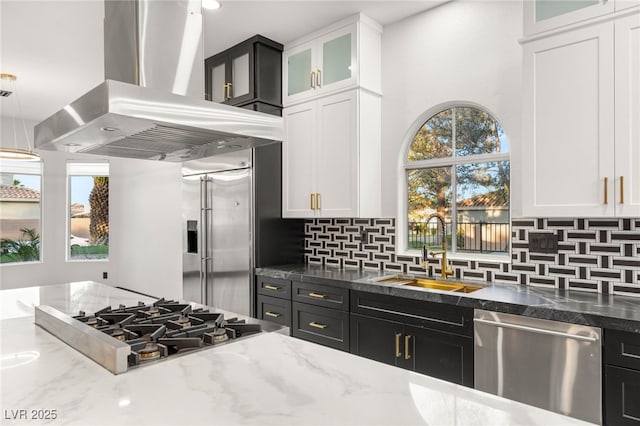 9029 Rivers Edge Dr, Las Vegas, NV 89117 - kitchen featuring island exhaust hood, stainless steel appliances, a sink, light stone counters, and white cabinets