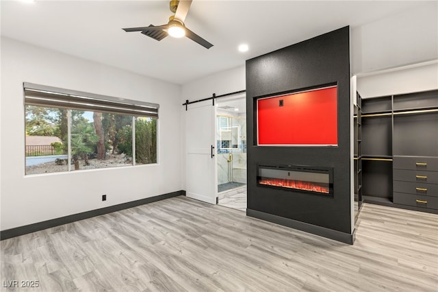 9029 Rivers Edge Dr, Las Vegas, NV 89117 - unfurnished living room with wood finished floors, a barn door, a ceiling fan, baseboards, and a glass covered fireplace