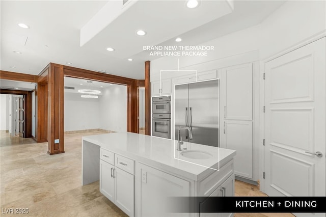 9101 Alta Dr Unit 102, Las Vegas, NV 89145 - kitchen featuring a sink, appliances with stainless steel finishes, a kitchen island with sink, white cabinetry, and light countertops