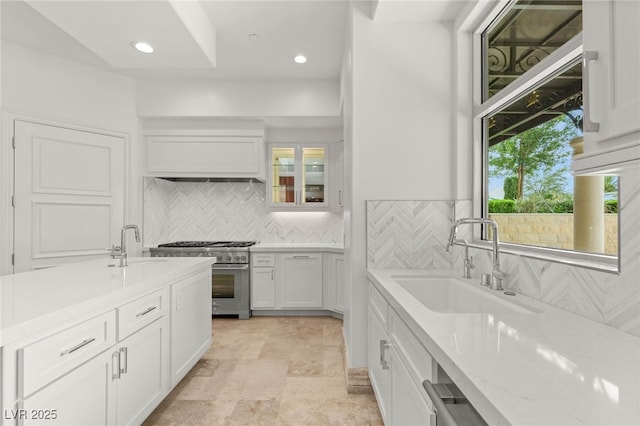 9101 Alta Dr Unit 102, Las Vegas, NV 89145 - kitchen with high end stove, white cabinets, a sink, decorative backsplash, and recessed lighting
