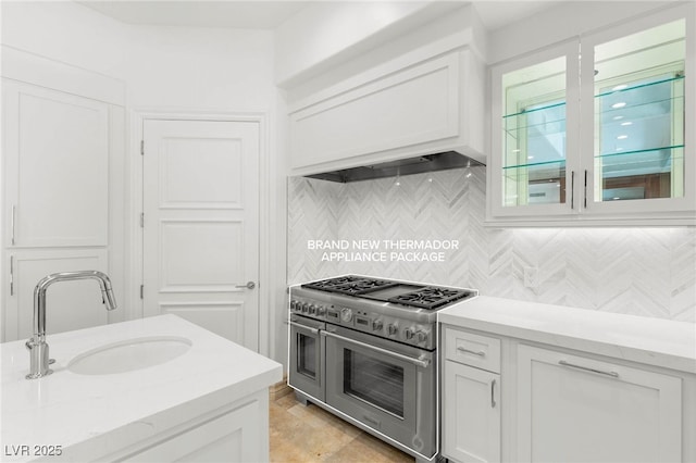 9101 Alta Dr Unit 102, Las Vegas, NV 89145 - kitchen with range with two ovens, a sink, white cabinetry, and decorative backsplash