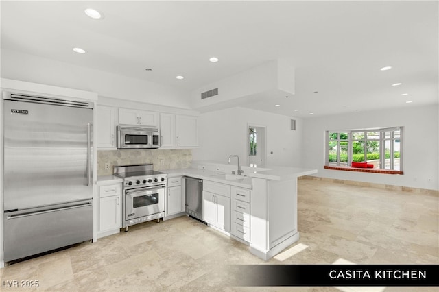 9101 Alta Dr Unit 102, Las Vegas, NV 89145 - kitchen with high end appliances, a peninsula, a sink, light countertops, and tasteful backsplash
