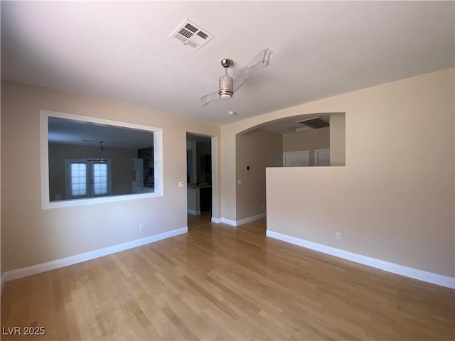 5376 S Conquistador St, Las Vegas, NV 89148 - empty room with arched walkways, baseboards, and light wood finished floors